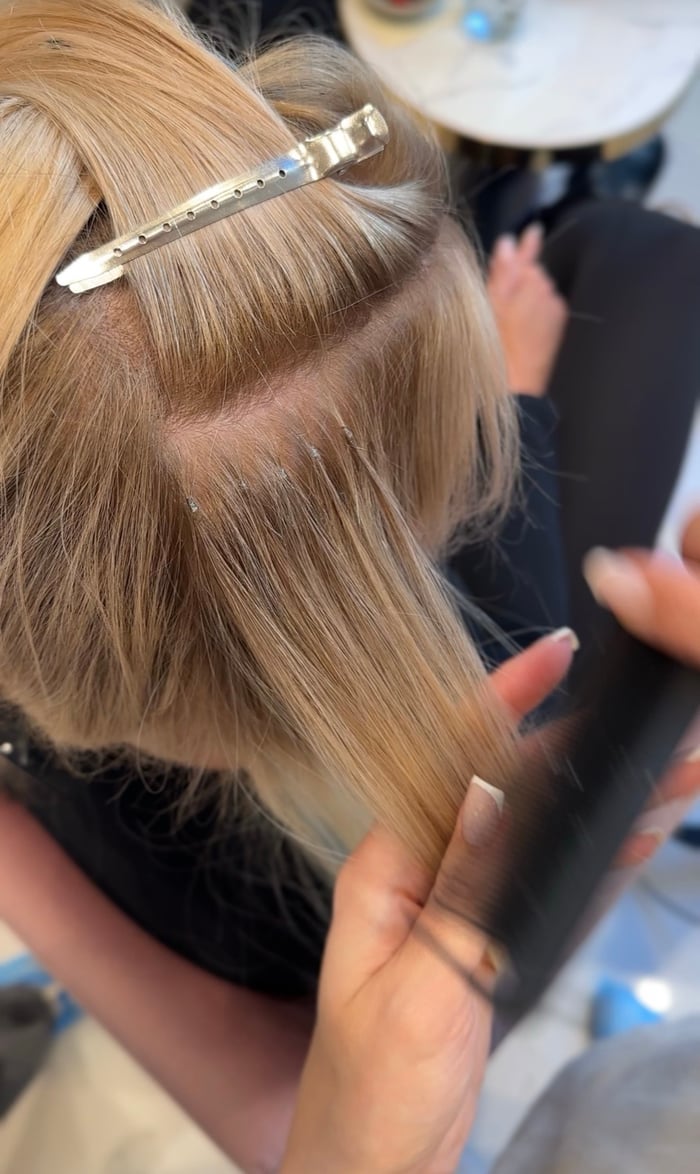 Nahaufnahme nahtloser Bondings im blonden Haar beim Glätten