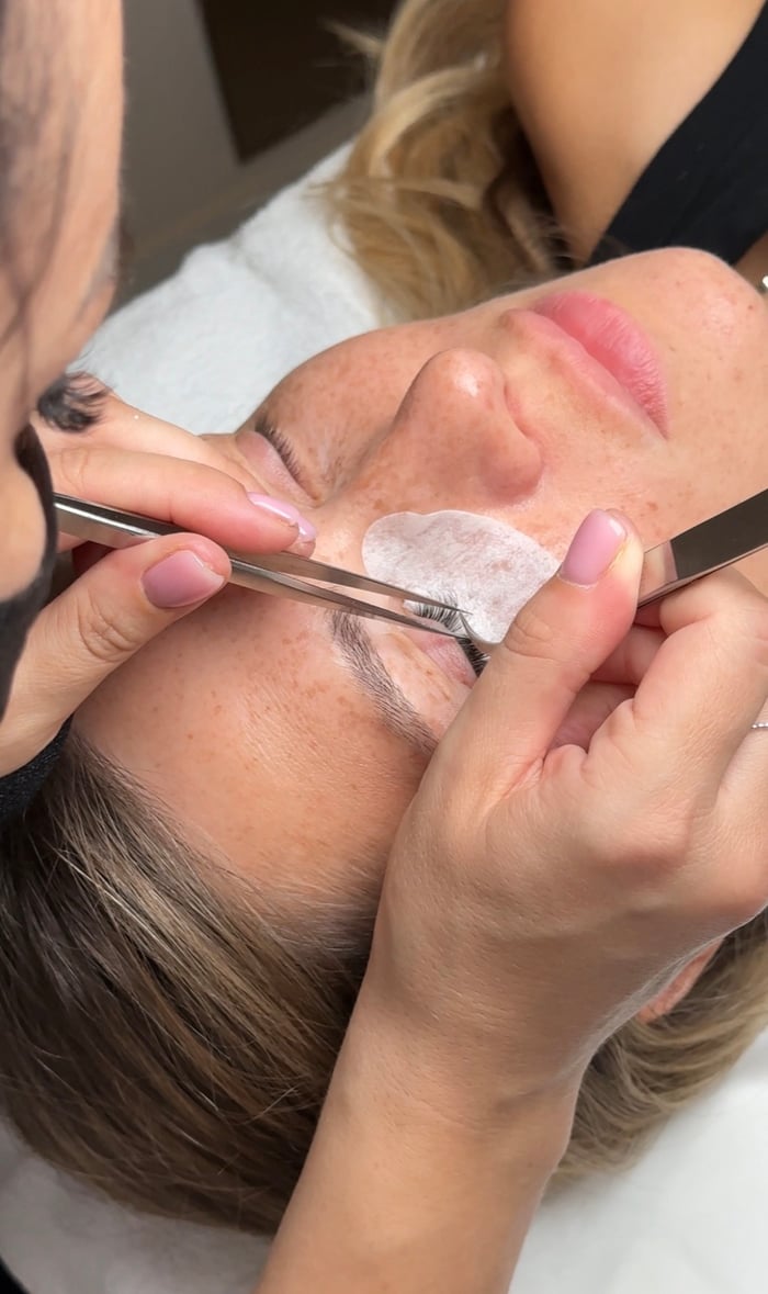 Wimpernverlängerung: Stylistin bringt einzelne Wimpern mit Pinzette an