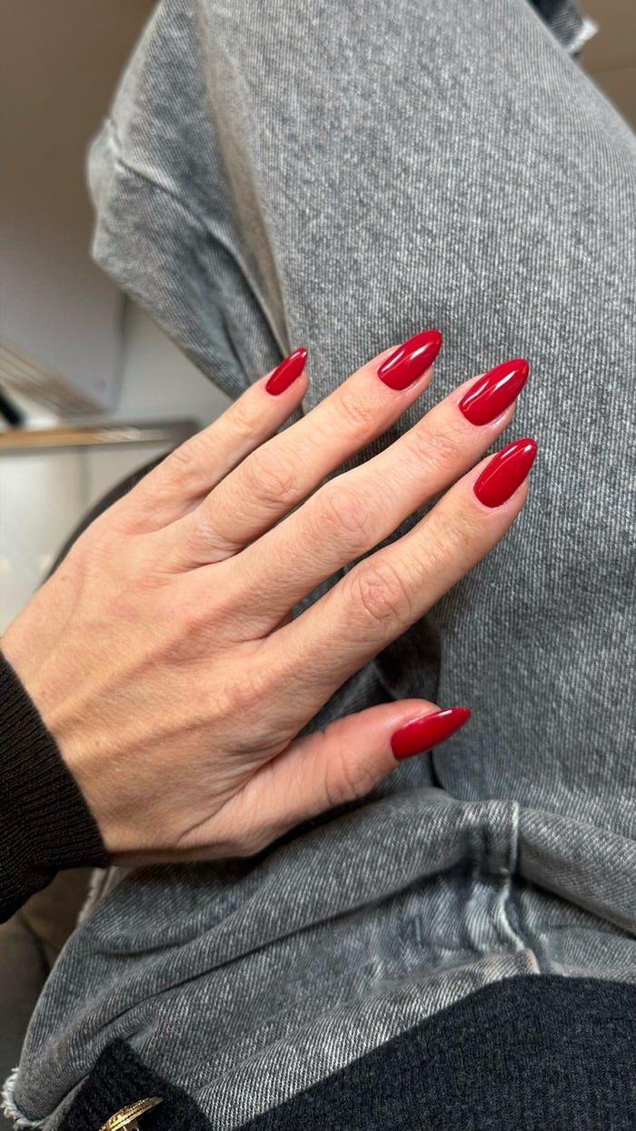 Gelnägel in klassischem Rot, Mandelform, Hand vor grauem Denim