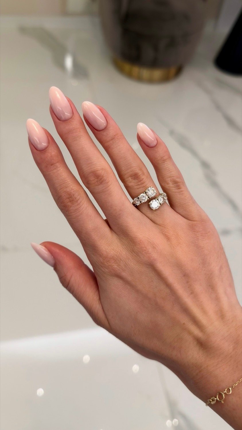 Elegante milchig-nude Babyboomer Nägel, Hand mit Diamantring auf Marmor