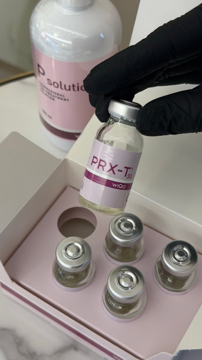 Kosmetikerin hält PRX-T33 Ampulle über das WiQo Peeling-Set