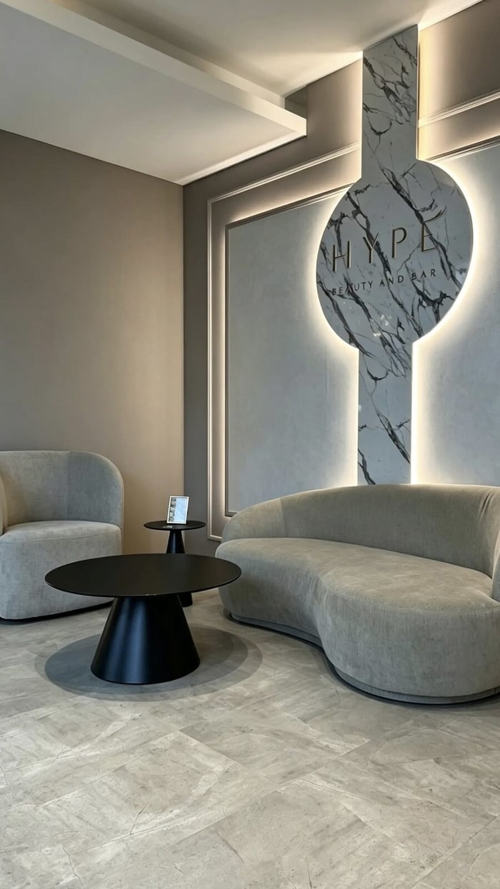 Geschwungenes Sofa vor der hinterleuchteten HYPE Wortmarke aus Marmor