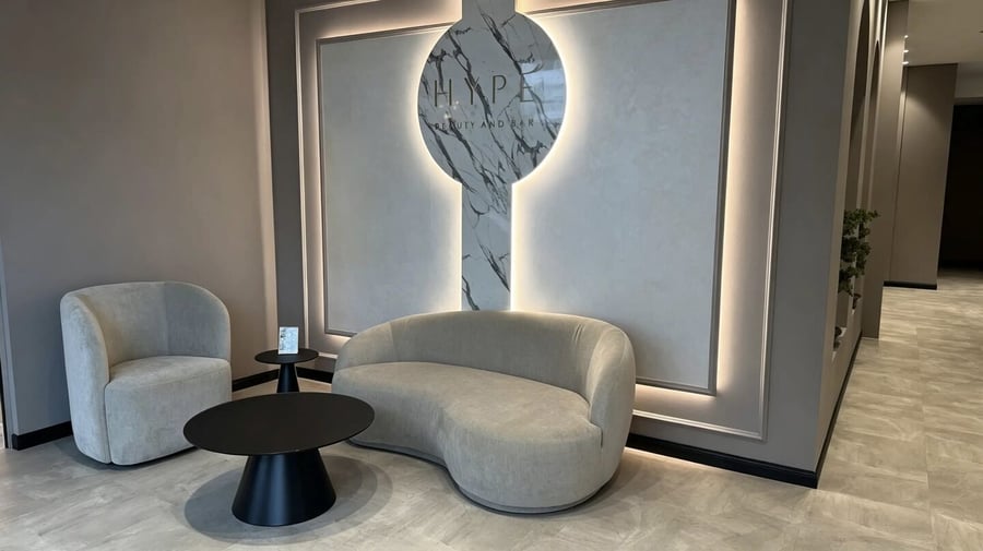 Sitzecke der HYPE Lounge mit Sessel und Sofa vor der beleuchteten Wortmarke
