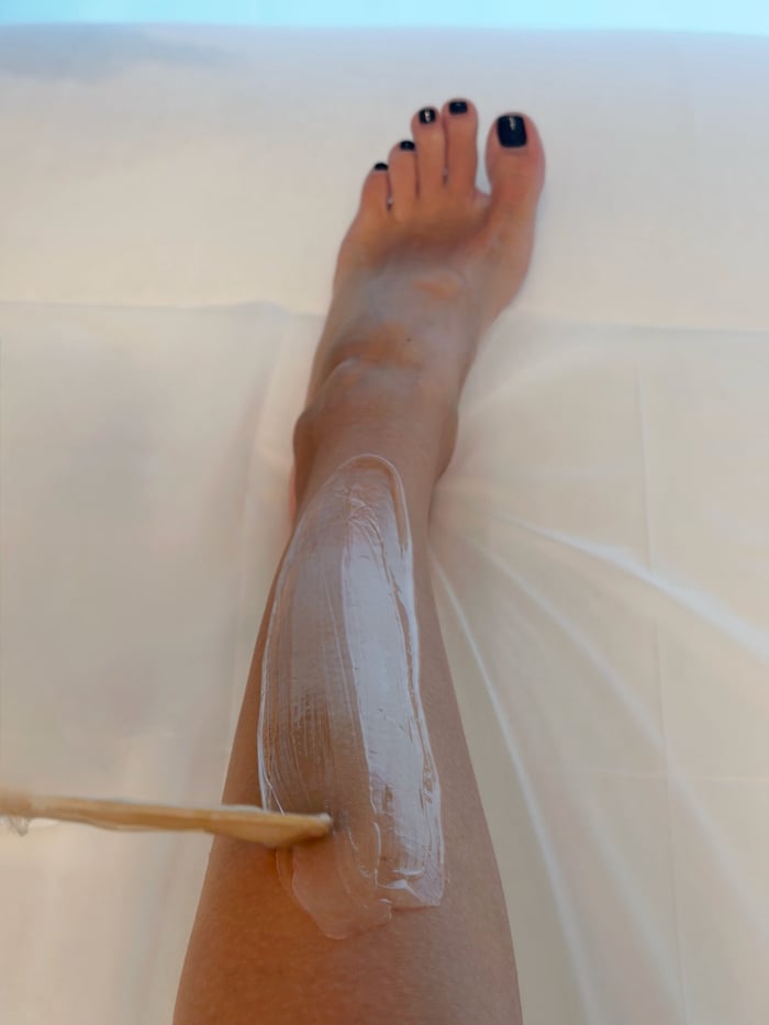 Sugaring-Behandlung am Bein mit Zuckerpaste