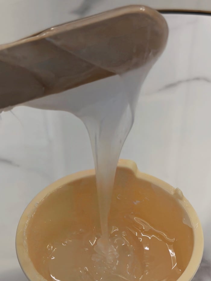 Zähflüssige Zuckerpaste läuft vom Spatel in den Tiegel