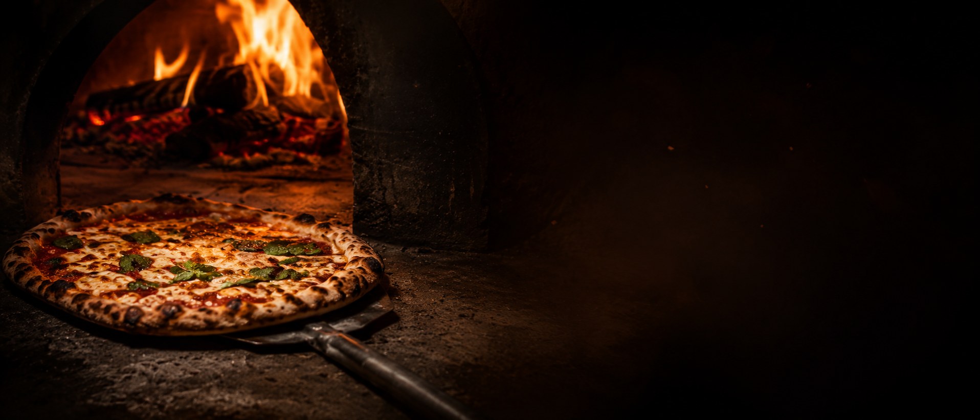 Steinofen-Pizza Margherita auf dem Schieber vor dem lodernden Holzofen von meynum