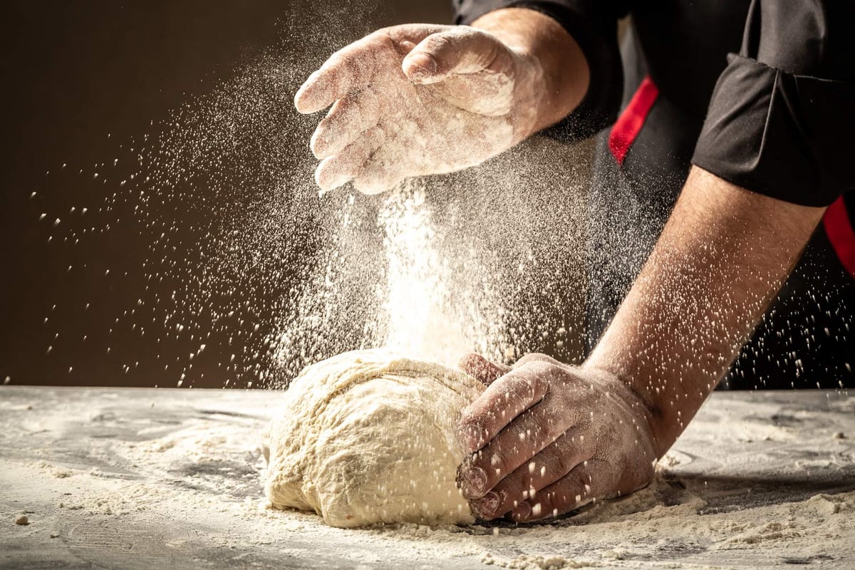Pizzabäcker bestäubt den 72-Stunden-Teig mit Mehl