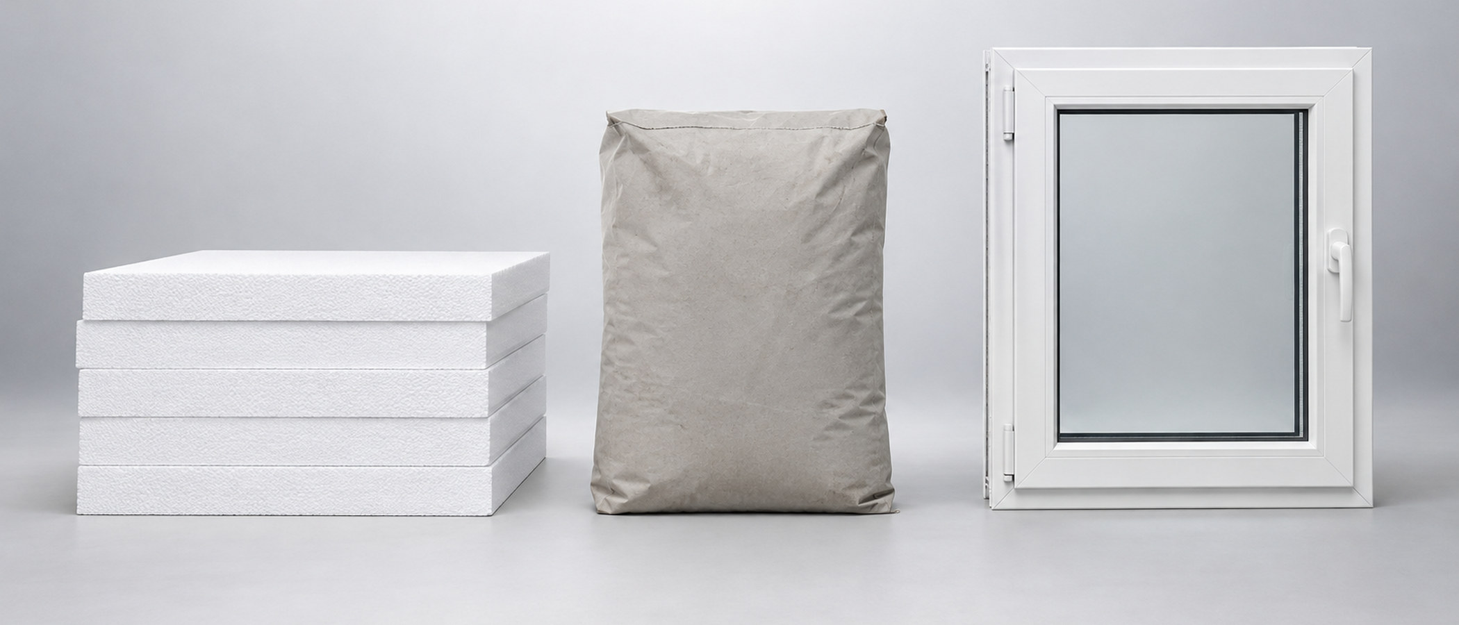 Studioaufnahme: Stapel Styropor-Dämmplatten, Zementsack und Kunststoff-Fensterelement nebeneinander