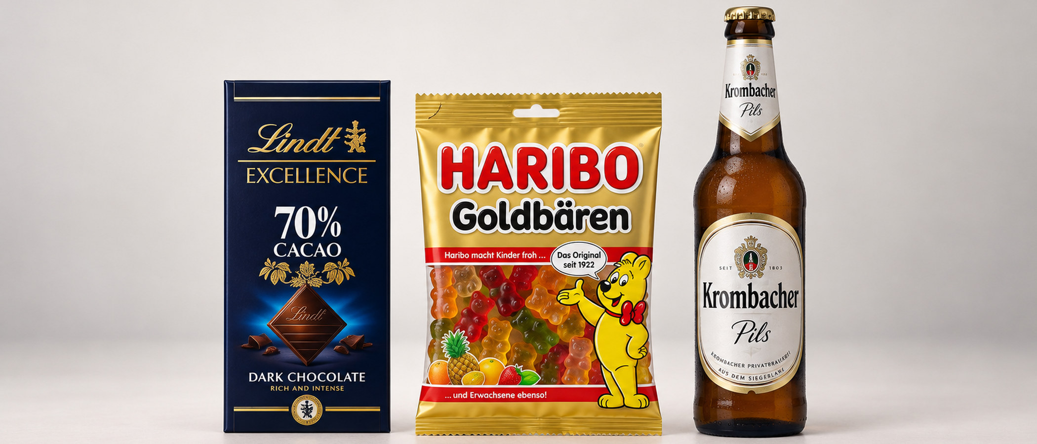 Studioaufnahme: Tafel Lindt-Schokolade, Tüte HARIBO Goldbären und Flasche Krombacher Pils nebeneinander