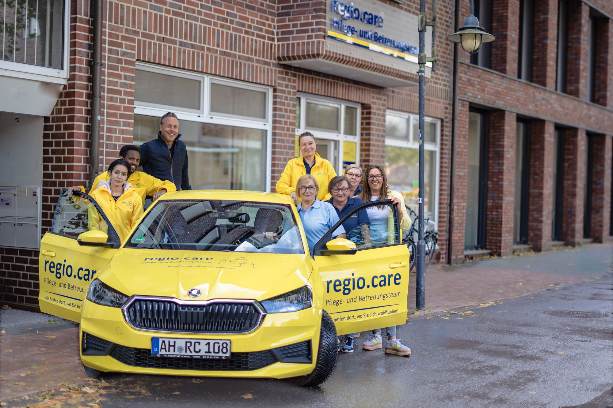Das regio.care Pflegeteam Ahaus mit Dienstwagen vor dem Büro