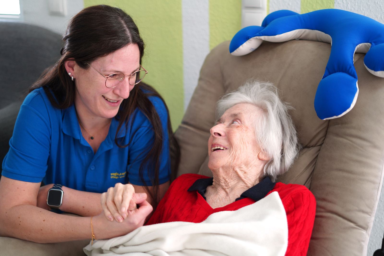 Mitarbeiterin hält die Hand einer Seniorin