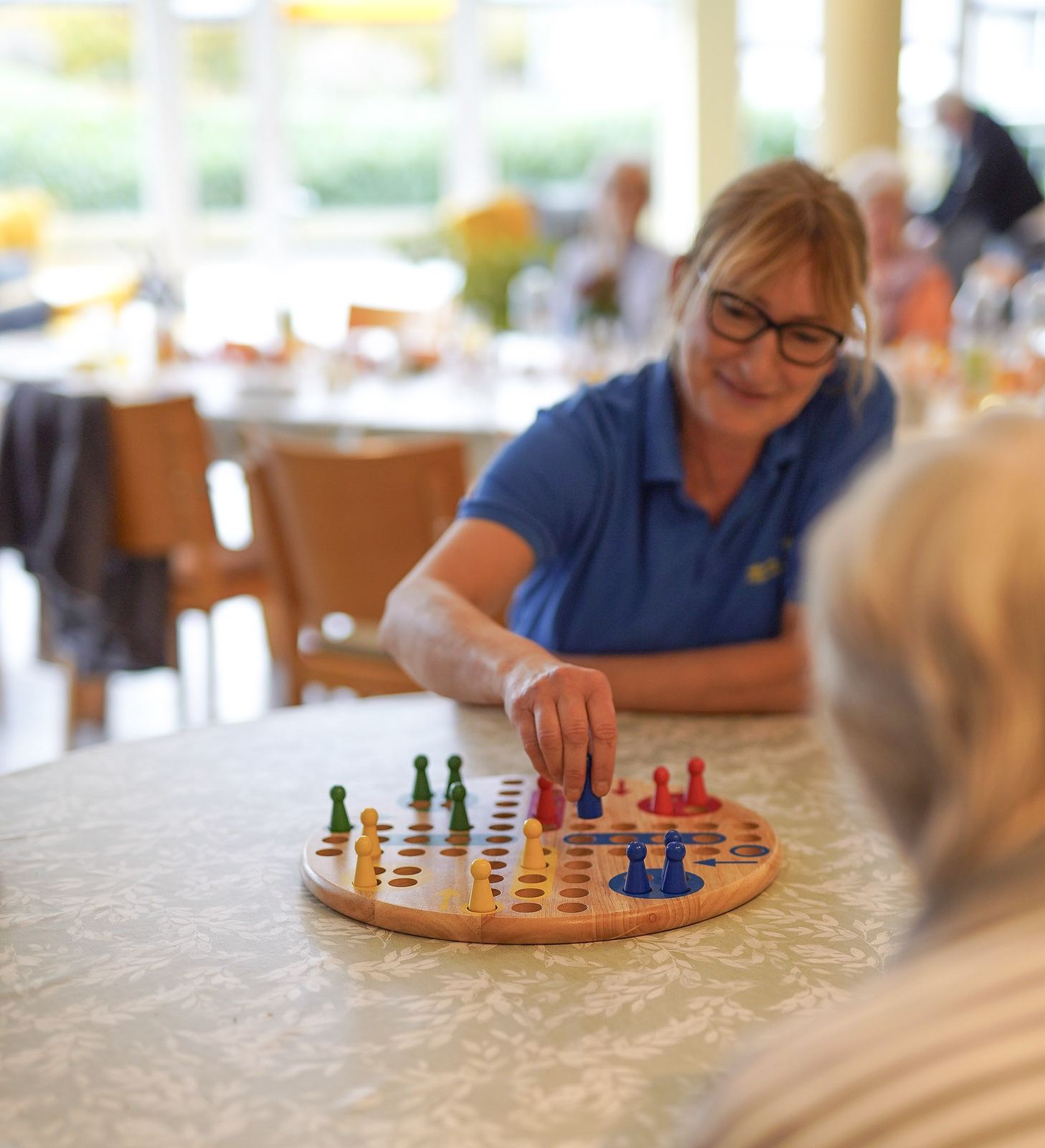 Mitarbeiterin spielt „Mensch ärgere Dich nicht“ mit Gästen