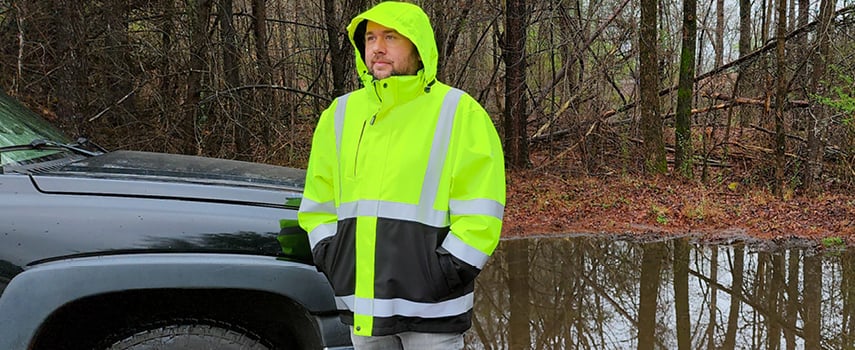 A man in wearing a high-visibility rain jacket working in the rain.