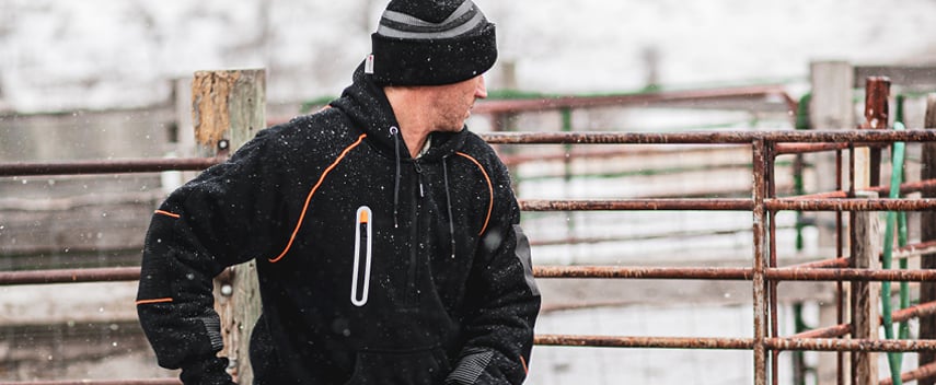 Man wearing a thermal hoodie works outside in the snow.