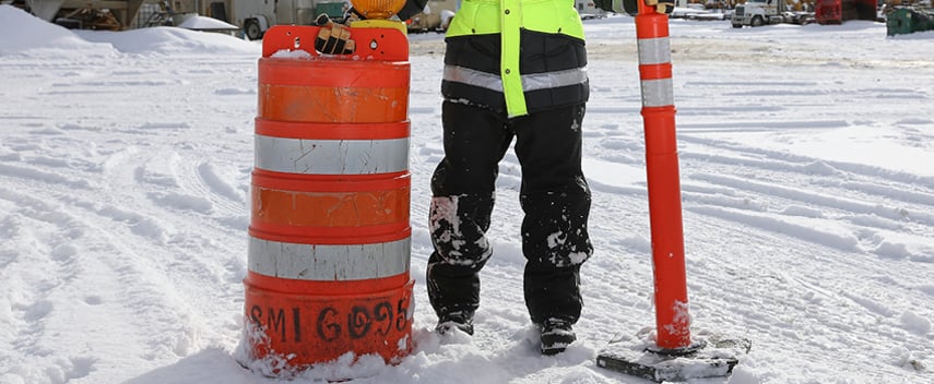 Person wearing insulated softshell work pants stands on a snowy construction site.