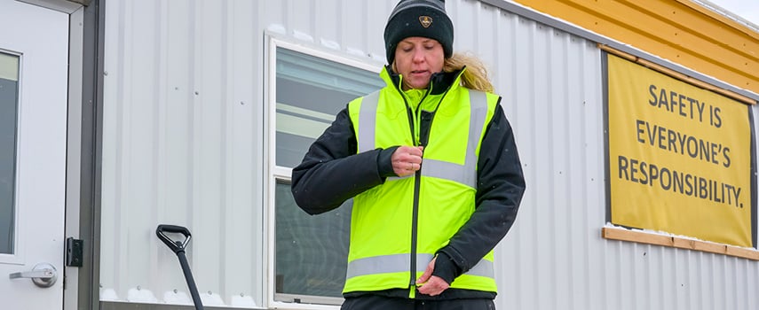 A woman putting on her hivis workwear.