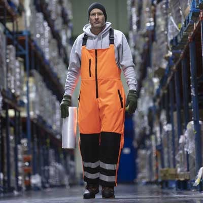 Man walking in a refrigerated warehouse wearing RefrigiWear Bib Overalls