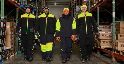 Four men walking in a warehouse, wearing insulated PPE