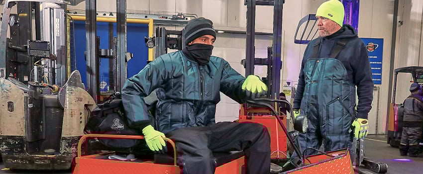 People operating machinery in a food processing plant are dressed in lightweight insulated freezerwear.