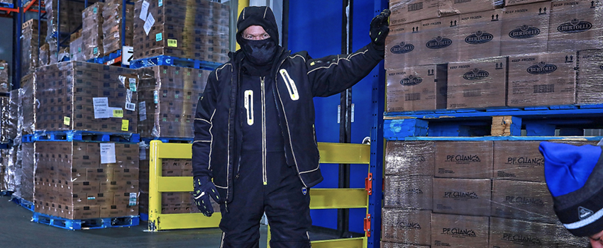 Man wearing a complete freezer suit and non-slip freezer boots works in a cold storage warehouse.