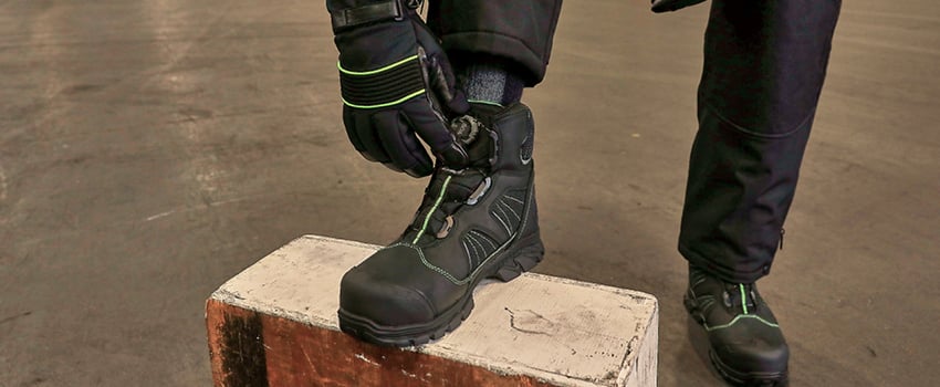 Person wearing insulated non-slip freezer boots works in a freezer warehouse.