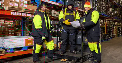 Three men working on a forklift, wearing insulated PPE
