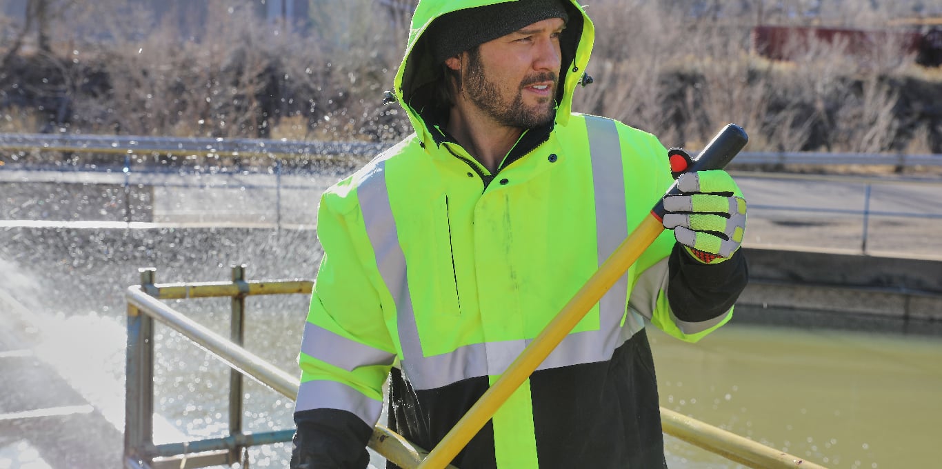 Man working outside in wet and cool spring weather wears high-visibility waterproof jacket.