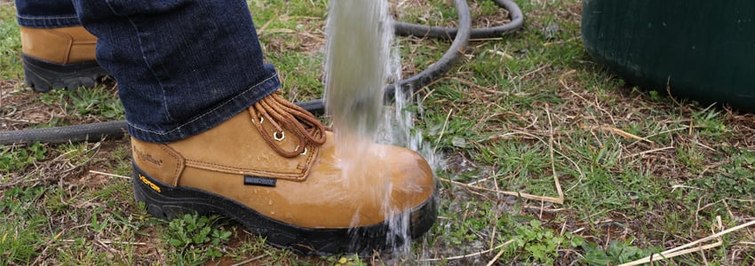 Construction worker washes concrete off a waterproof work boot.