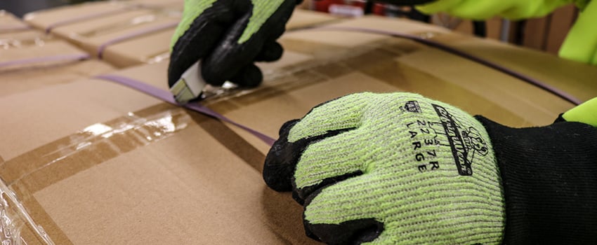 Person using a box cutter wears cut-resistant gloves.