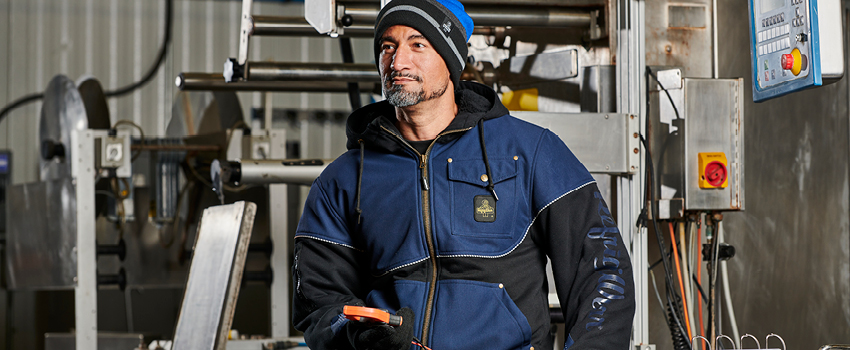 Man working in a climate controlled food processing facility wears an insulated zip-up hoodie and  knit gloves.