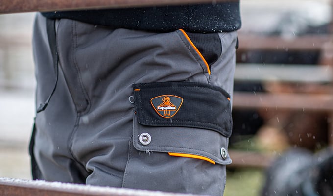 Man wearing insulated work pants works outdoors on a ranch.