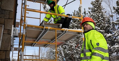 Two men working on a scaffold in hivis gear.