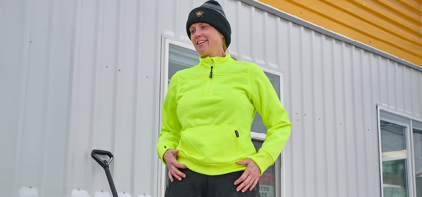 Female construction worker wearing properly fitting PPE, including a hard hat and safety vest, representing OSHA's new rule for gender-specific safety gear.