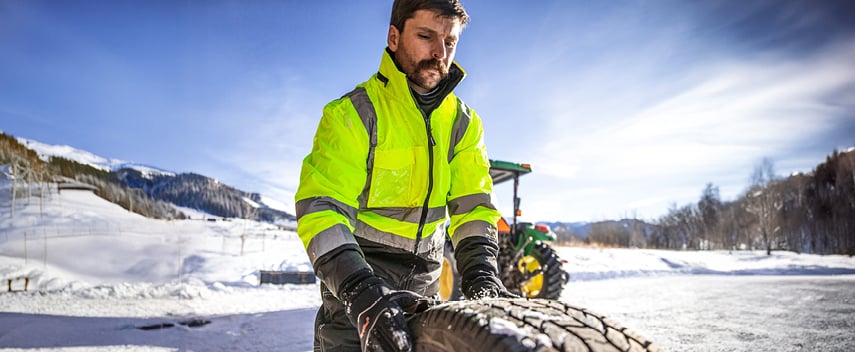 Man wearing waterproof insulated workwear works in the snow