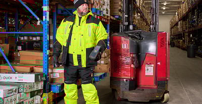A man standing next to a forklift wearing Hivis Gear.