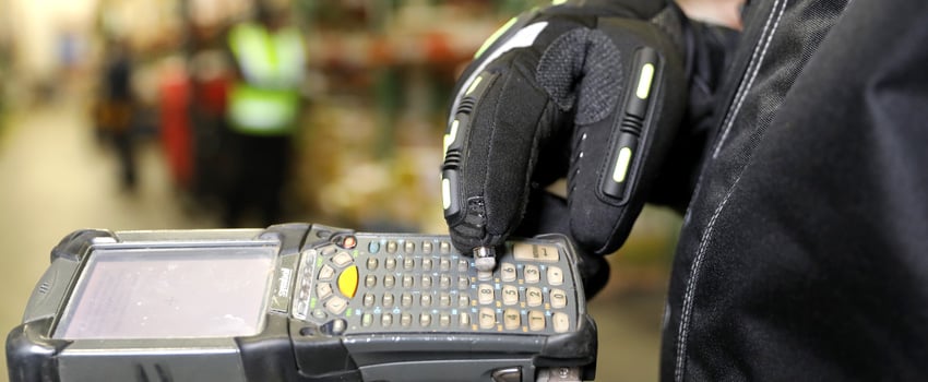 Person wearing Touch-Rite insulated work gloves uses a touchscreen handheld scanner.