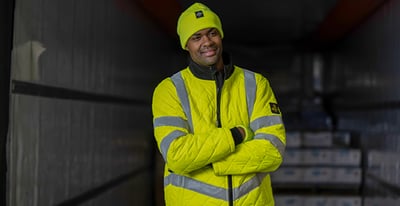 A man arms crossed in hivis jacket .