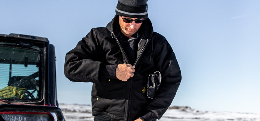 Man zipping up a RefrigiWear jacket in the snow