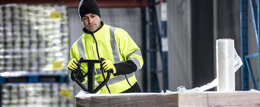 Person using a pallet jack in a food processing facility wears an insulated softshell jacket.