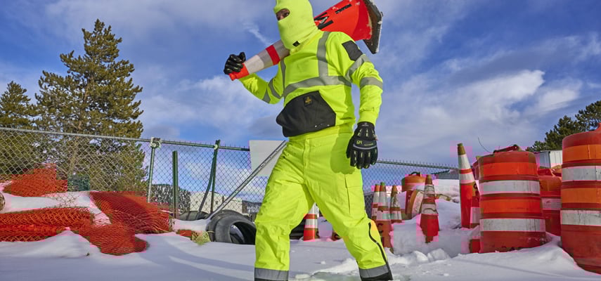 Man Walking in the snow wearing hivis workwear.