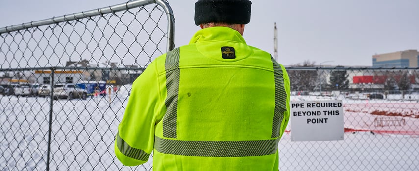 A man working in front of a gate in hivis workwear.