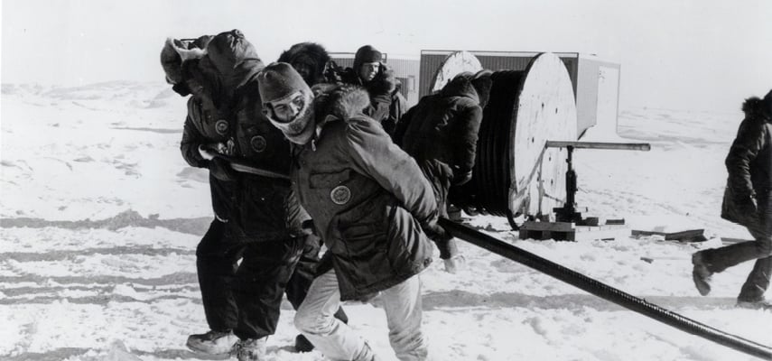 Black and white phote of men in cold weather gear working outside in Alaska.