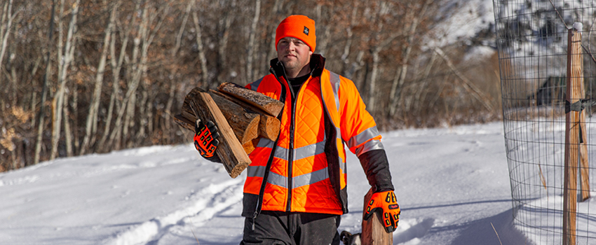 Man working outside in winter wears a base layer, thermal mid-layer jacket and a water-repellent over coat in high-visibility orange.