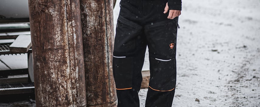 Man wearing insulated sweatpants works in the snow.
