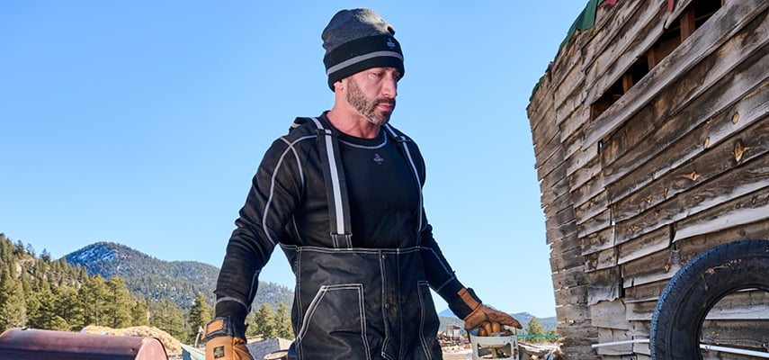 A man in overalls working outside.