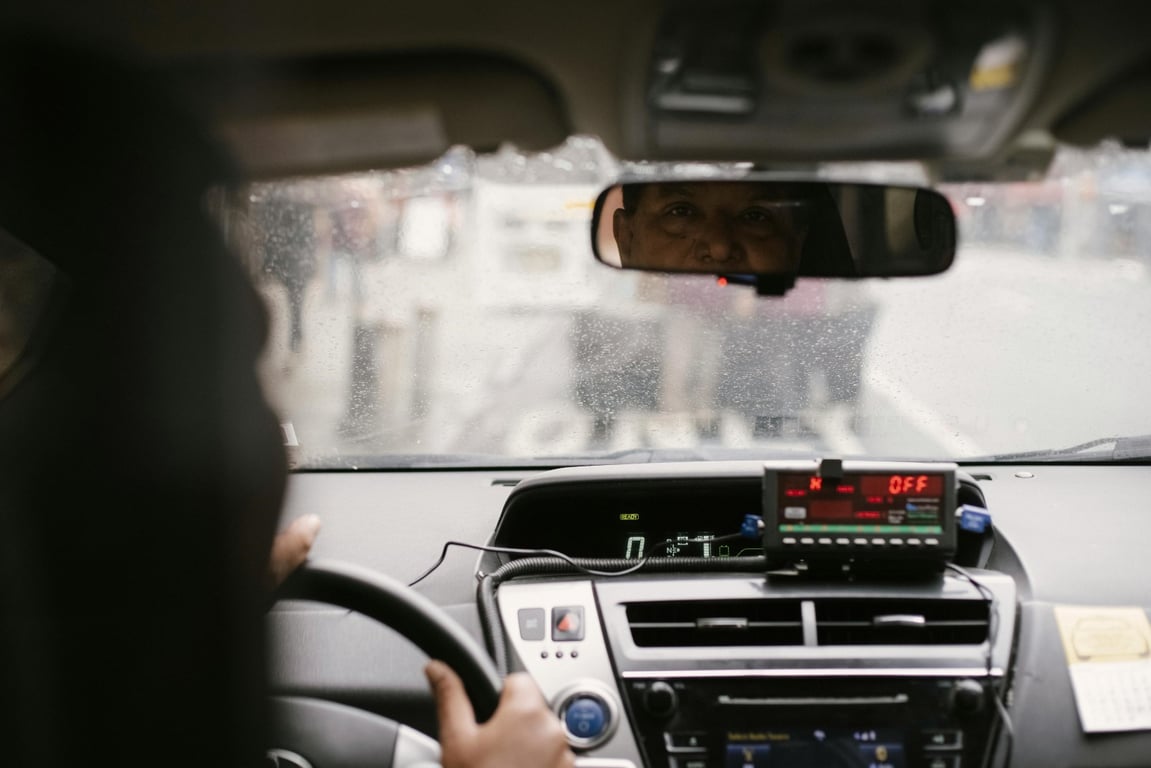 An image of a person looking at a back mirror in a car