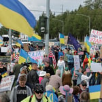 Otro manifestante sostenía un cartel azul y amarillo con mapas de Ucrania y Alaska y las palabras “Manos fuera – No más rusos”.