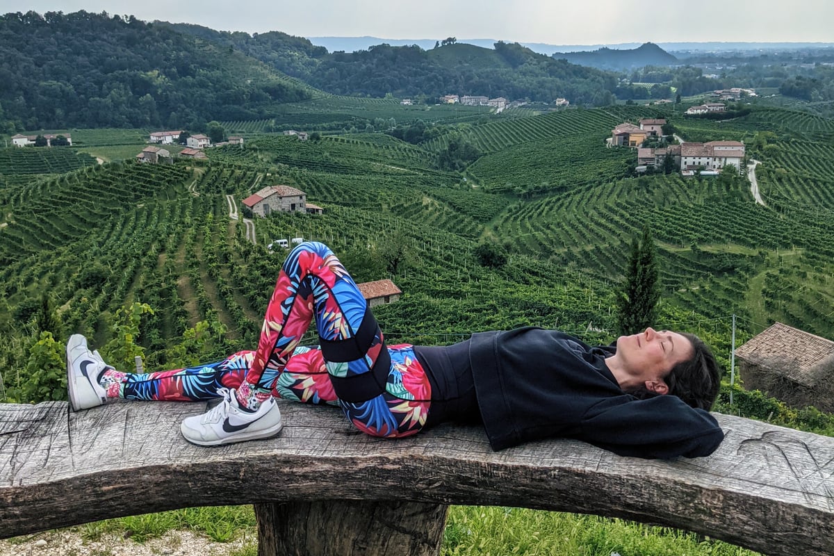 Alexandra vor Weinbergen liegend. Sportliches Outfit.