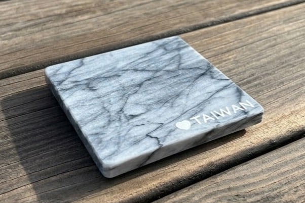 A Hualien marble coaster engraved with a heart and the word TAIWAN, sitting on weathered wooden planks