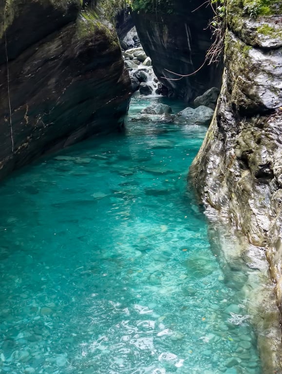 Emerald creek pool with waterfall, Hualien — turquoise water under granite walls, smooth boulder visible through clear water